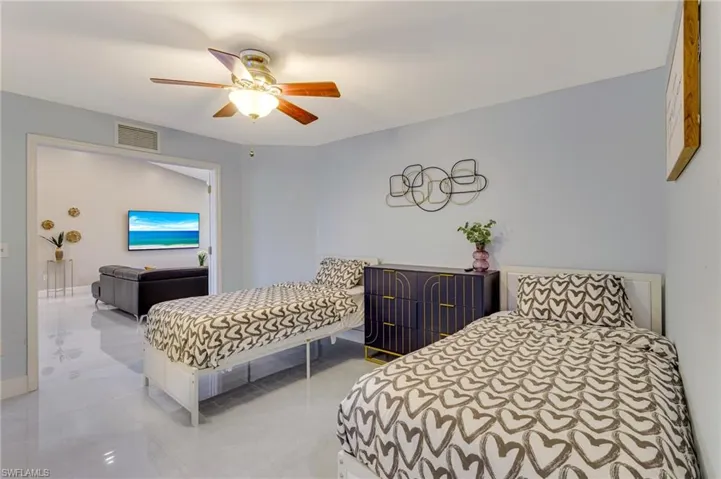 Tiled bedroom featuring ceiling fan and visible vents
