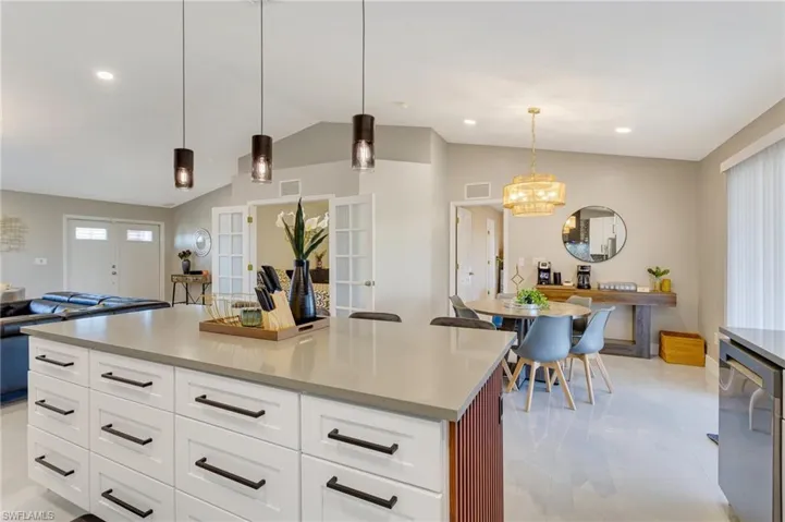 Kitchen featuring open floor plan, light countertops, visible vents, lofted ceiling, and pendant lighting