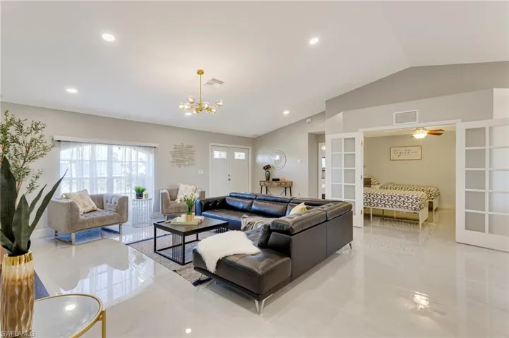 Living room with visible vents, vaulted ceiling, a chandelier, recessed lighting, and french doors