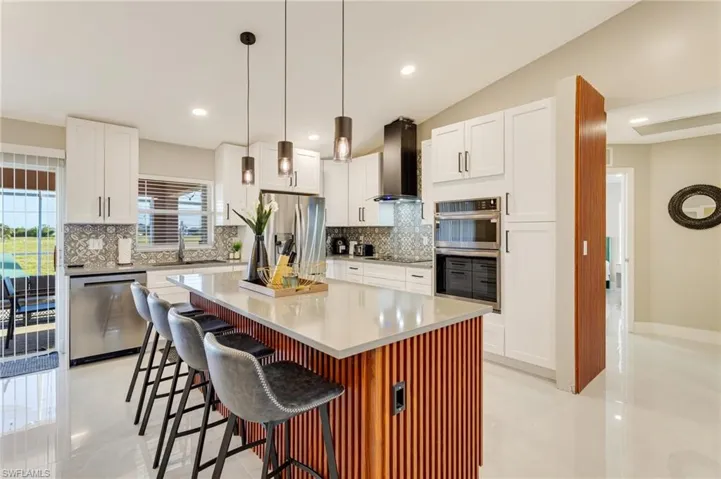 Kitchen featuring a sink, tasteful backsplash, wall chimney exhaust hood, and stainless steel appliances