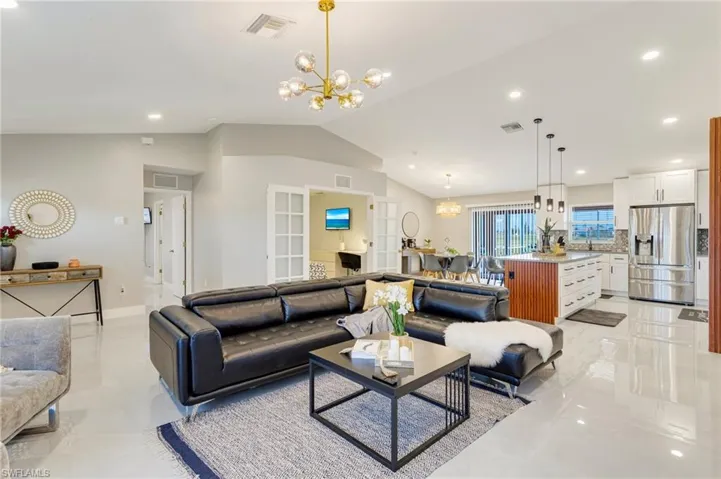 Living area with visible vents, an inviting chandelier, and lofted ceiling