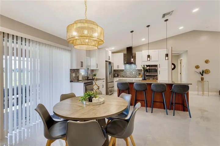 Dining space with visible vents, a notable chandelier, and vaulted ceiling