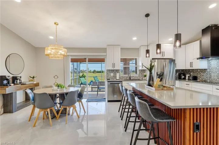 Kitchen featuring a kitchen bar, decorative backsplash, wall chimney range hood, and stainless steel appliances