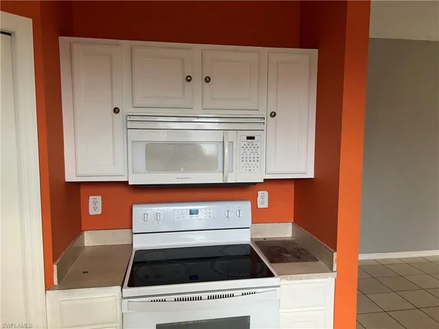 Kitchen featuring white appliances, white cabinets, and light countertops