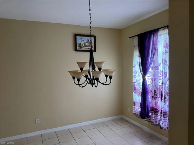 Unfurnished dining area with baseboards and a chandelier
