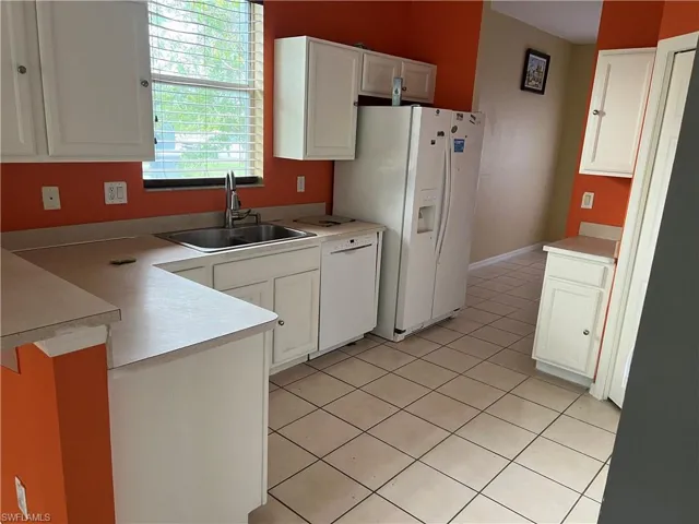 Kitchen featuring a sink, white appliances, a peninsula, and white cabinets