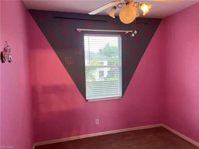 Carpeted spare room with baseboards and ceiling fan