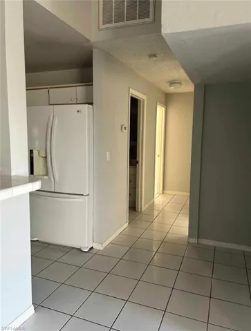 Kitchen featuring white refrigerator with ice dispenser and light tile patterned floors