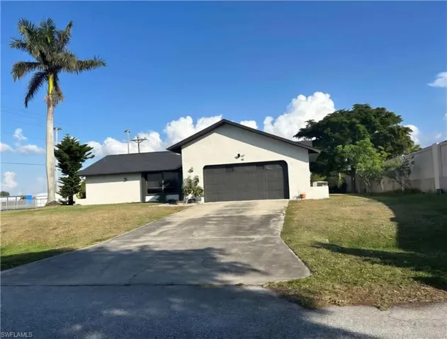 Ranch-style home with a front yard, stucco siding, concrete driveway, and an attached garage