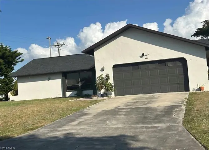 View of front of property with stucco siding, a front lawn, driveway, and a garage