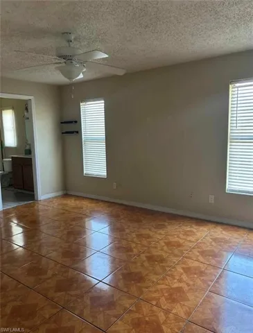 Spare room with a textured ceiling, ceiling fan, and light tile patterned flooring
