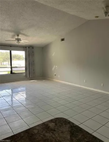 Spare room featuring ceiling fan, a textured ceiling, and light tile patterned floors