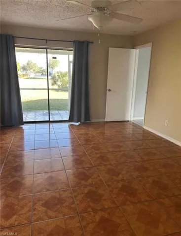 Spare room with a textured ceiling, ceiling fan, and dark tile patterned floors