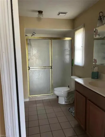 Bathroom with vanity, light tile patterned floors, and a stall shower