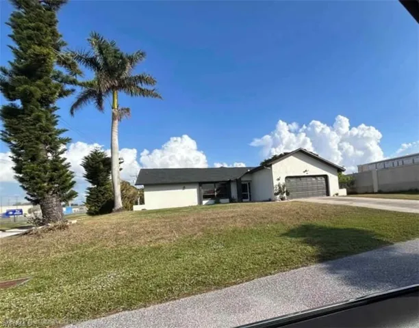 Single story home with a front yard, stucco siding, driveway, and an attached garage