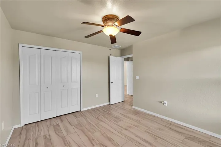 Unfurnished bedroom with ceiling fan, a closet, and light wood-style flooring