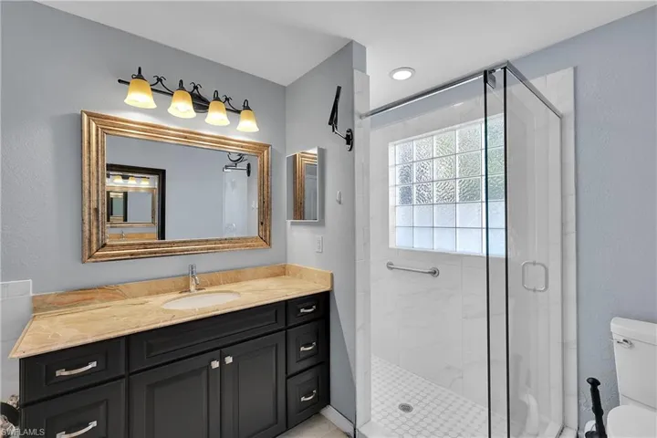 Full bath featuring vanity, a shower stall, and a textured wall