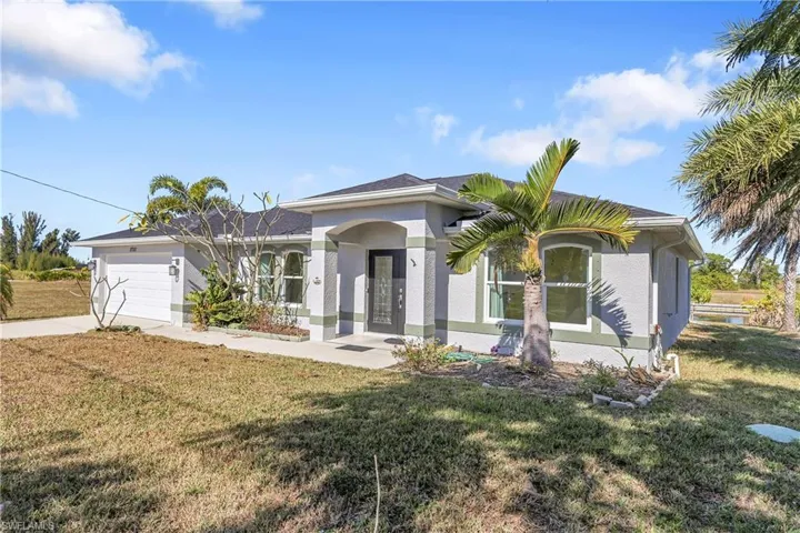 View of front of house featuring a front lawn, driveway, stucco siding, and a garage