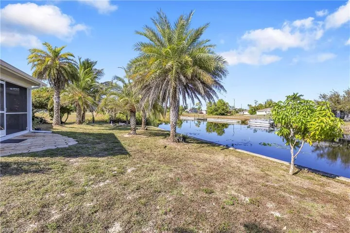 View of grassy yard featuring a water view, a patio area, and a sunroom