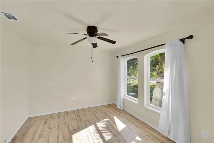 Empty room with wood tiled floors and a ceiling fan