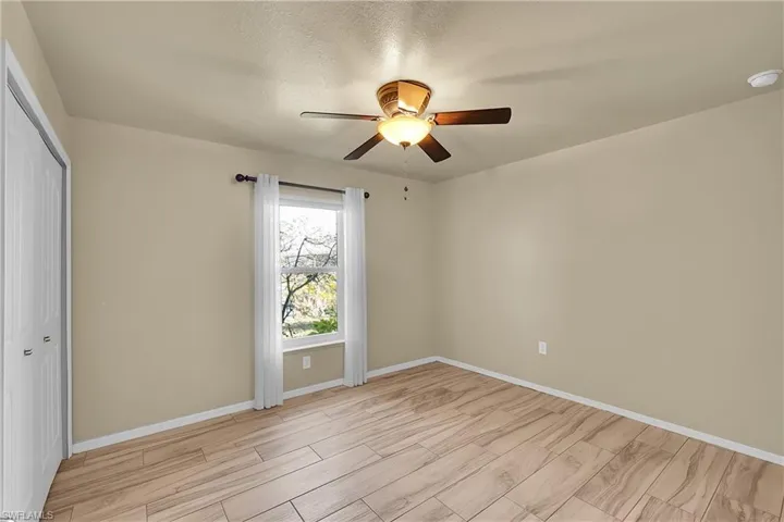 Unfurnished bedroom with a closet, ceiling fan, wood finish floors, and a textured ceiling