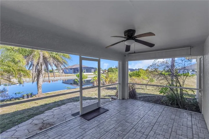 Unfurnished sunroom featuring a ceiling fan and a water view