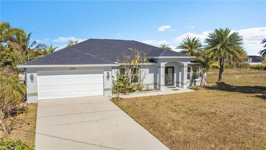 View of front of property with stucco siding, a front lawn, concrete driveway, a garage, and a shingled roof