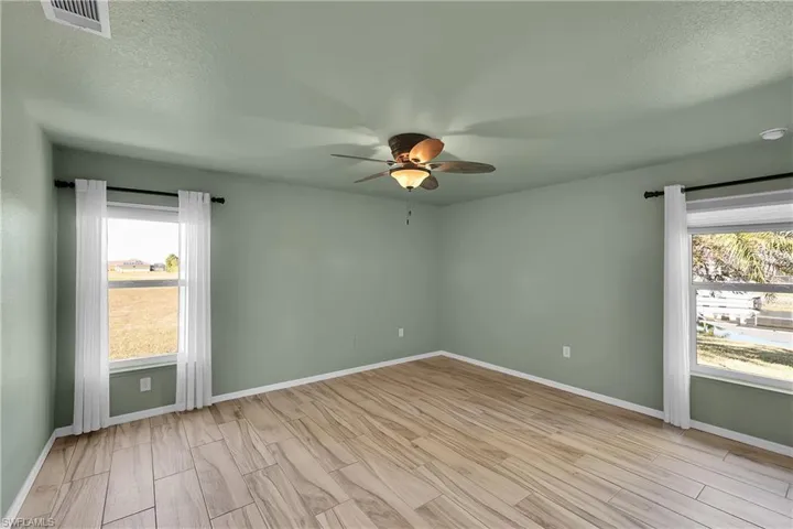 Unfurnished room with a textured ceiling, healthy amount of natural light, wood tiled floors, and a ceiling fan