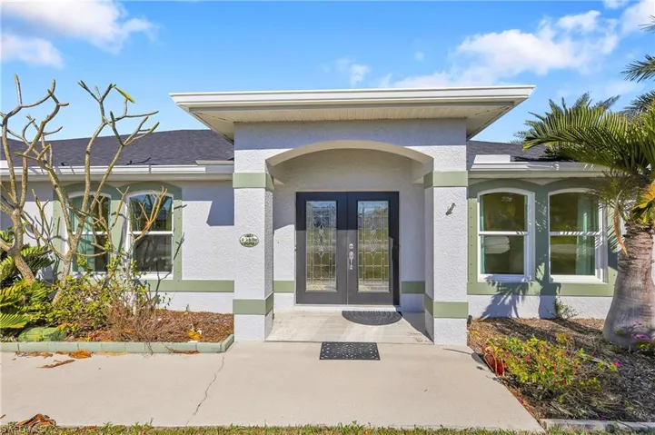 Doorway to property with stucco siding, a shingled roof, and french doors