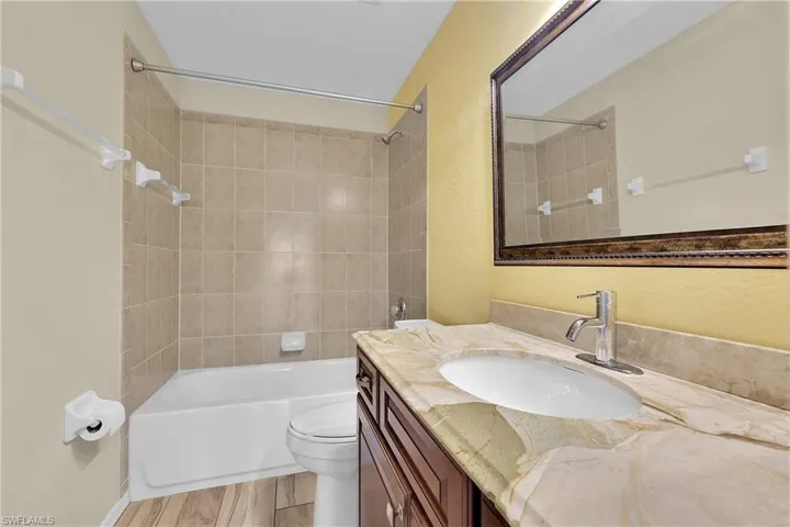 Bathroom featuring shower / bathtub combination, vanity, light wood-style floors, and a textured wall