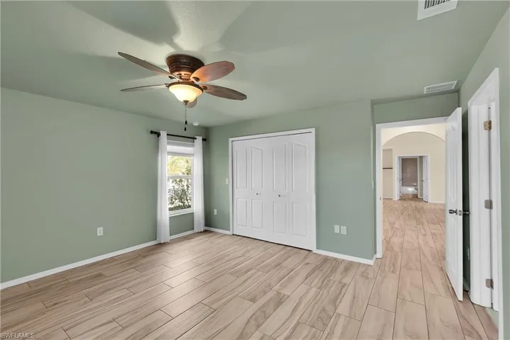 Unfurnished bedroom featuring arched walkways, ceiling fan, a closet, and wood tiled floors