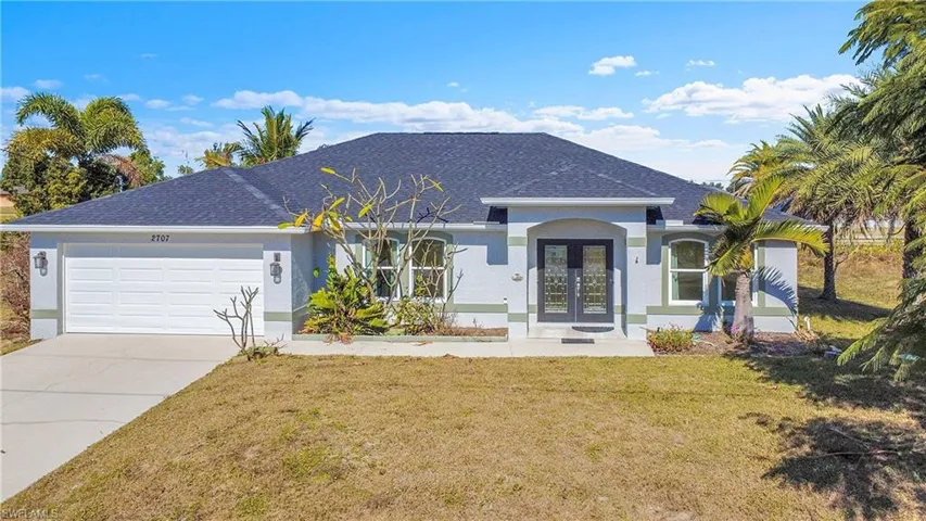 View of front of home with stucco siding, a front yard, french doors, concrete driveway, and a garage