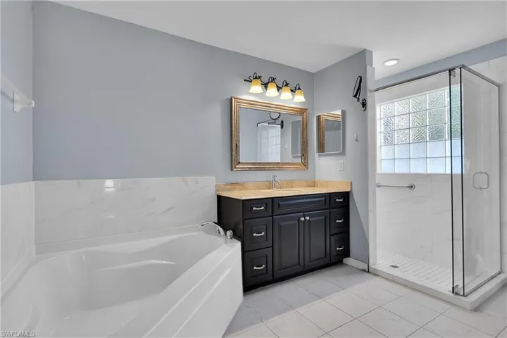 Bathroom with vanity, a bath, and a stall shower