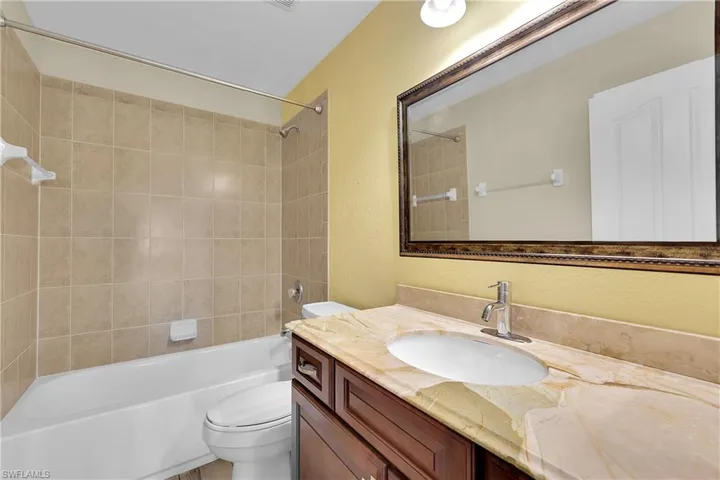 Bathroom featuring a textured wall, tub / shower combination, and vanity