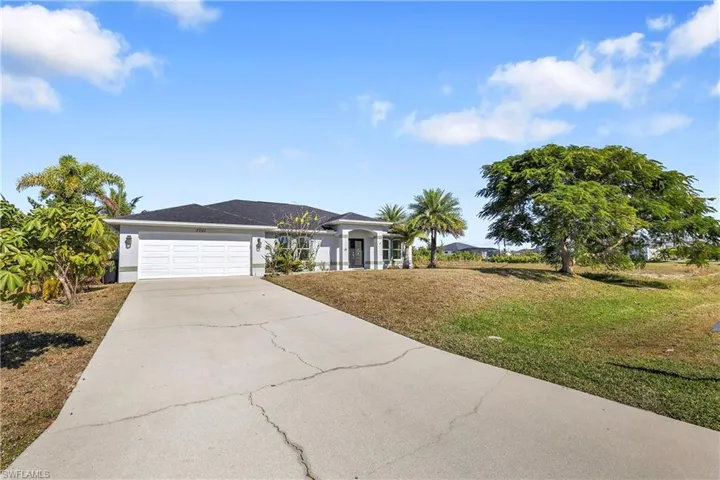 Ranch-style house featuring a front lawn, concrete driveway, and an attached garage
