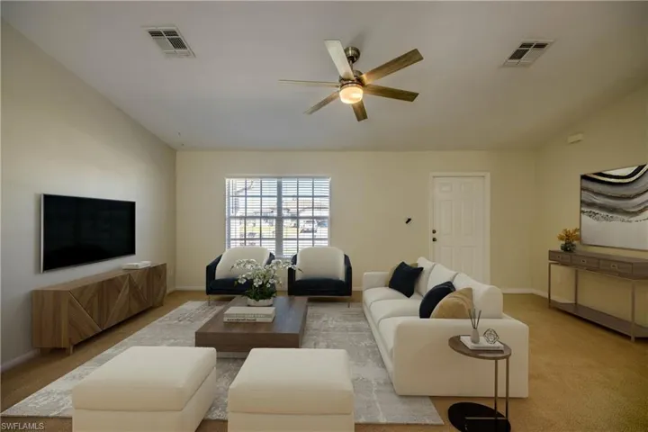 Living area with visible vents, ceiling fan, and vaulted ceiling