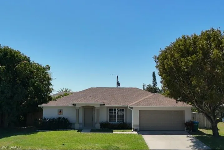 Single story home featuring a front yard, fence, driveway, an attached garage, and stucco siding