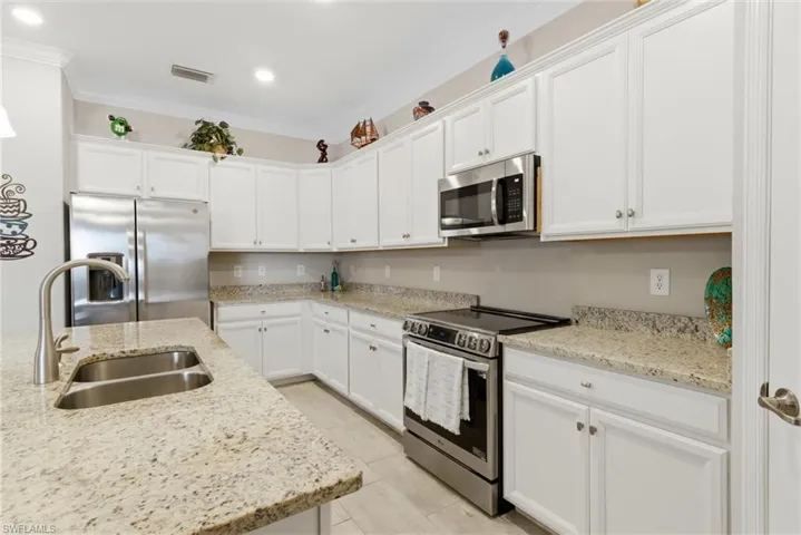 Upgraded kitchen featuring granite countertops, induction range, newer appliances, and a generous walk-in pantry.