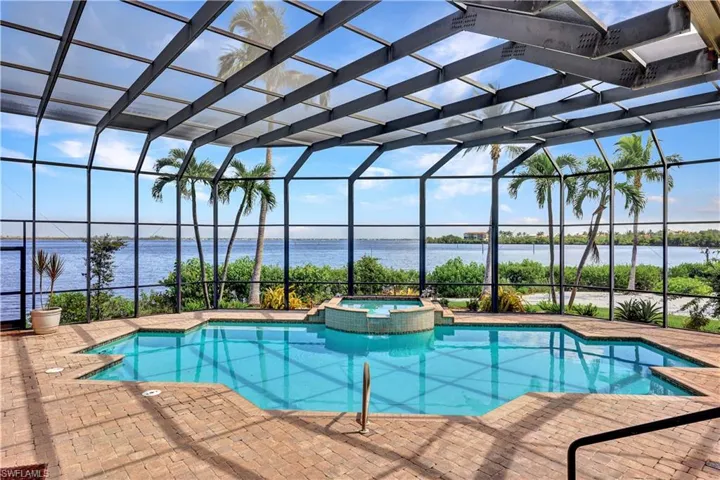 View of pool featuring a lanai, an in ground hot tub, a patio area, and a water view