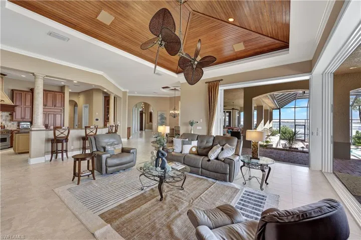 Expansive family room with retractable sliders with custom ceiling details, fireplace and endless water views