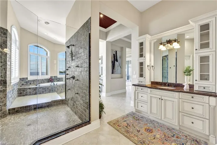 Bathroom with crown molding, vanity, and plus walk in shower
