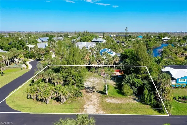 Aerial perspective of suburban area with property parcel outlined and a tree filled landscape