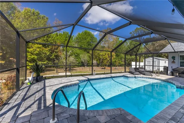 Swimming pool with a shed, a sunroom, a patio area, and glass enclosure