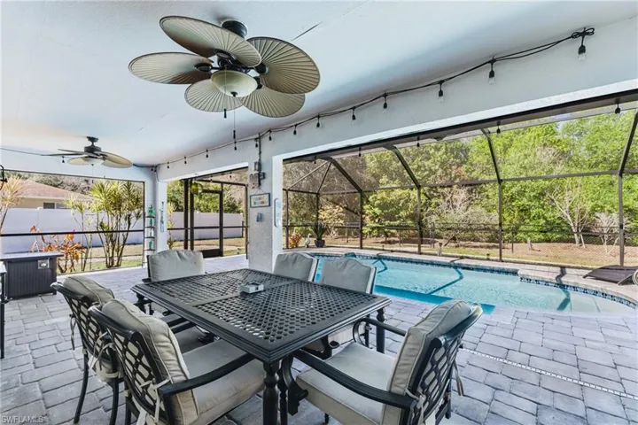 View of swimming pool featuring a lanai, a sunroom, patio surround, and outdoor dining area
