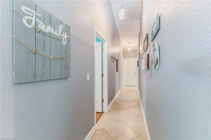 Hall featuring a textured wall and light tile patterned floors