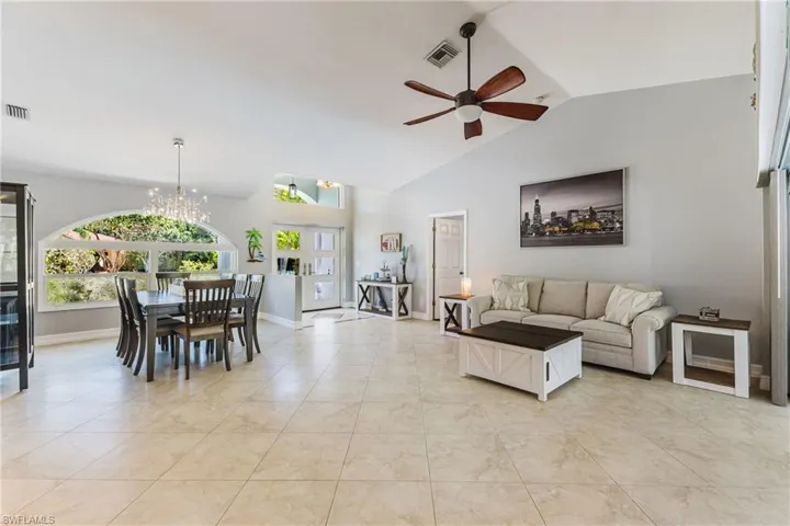 Living area featuring lofted ceiling, suspended lighting, a ceiling fan, and light tile patterned flooring
