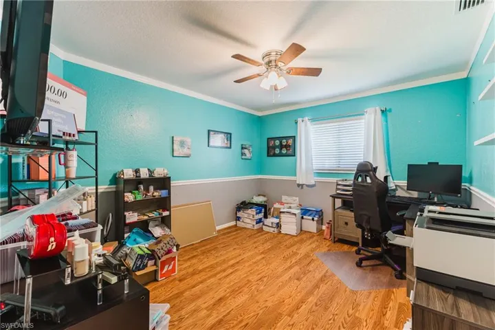 Office with light wood-style floors, a textured ceiling, a textured wall, and ceiling fan