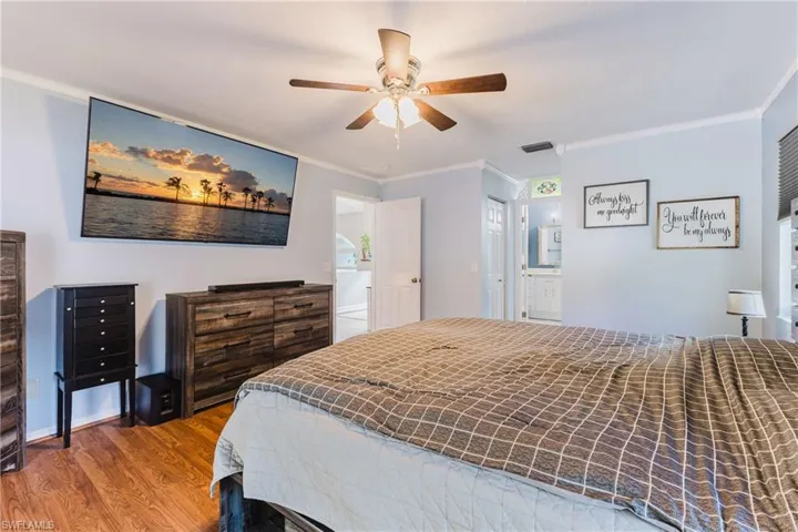 Bedroom with ornamental molding, wood finished floors, and a ceiling fan