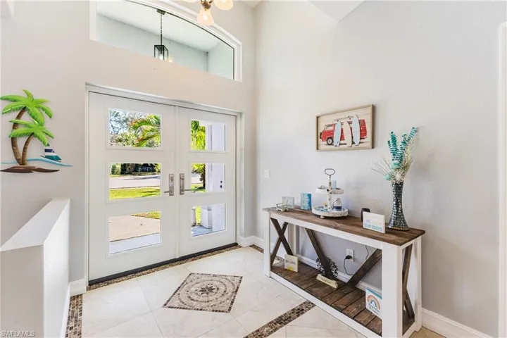 Entrance foyer with french doors, inlaid floor details, a high ceiling, and light tile patterned flooring