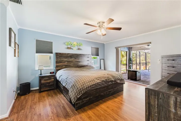 Bedroom with access to outside, ornamental molding, wood finished floors, and a ceiling fan